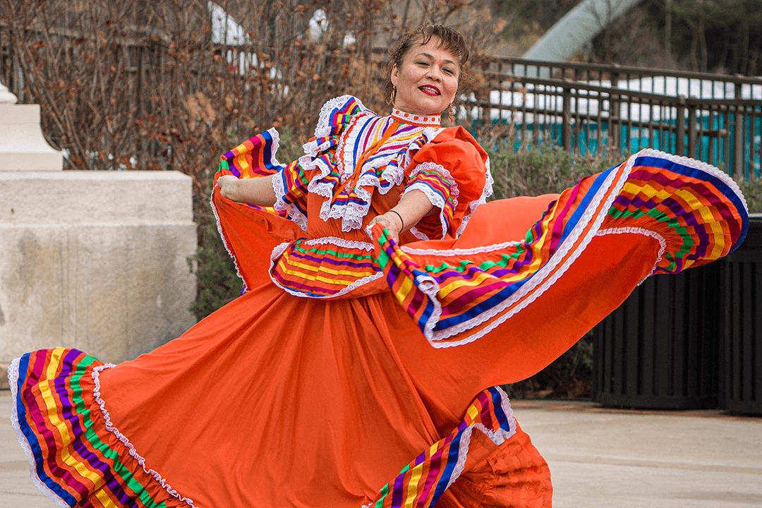 Image of Folkloric Dancer in a bright orange traditional dress dancing in front of Atascadero City Hall - Photo by Keith Bergher